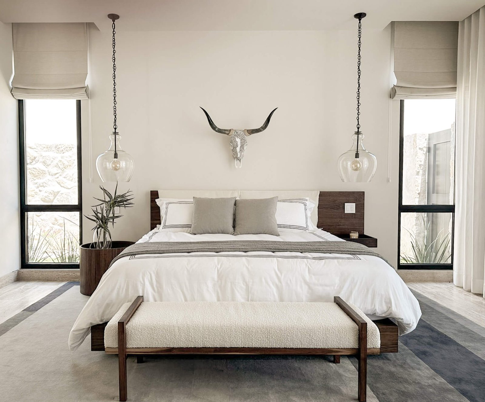 Cabokero artwork above the bed in a neutral bedroom with a bench.