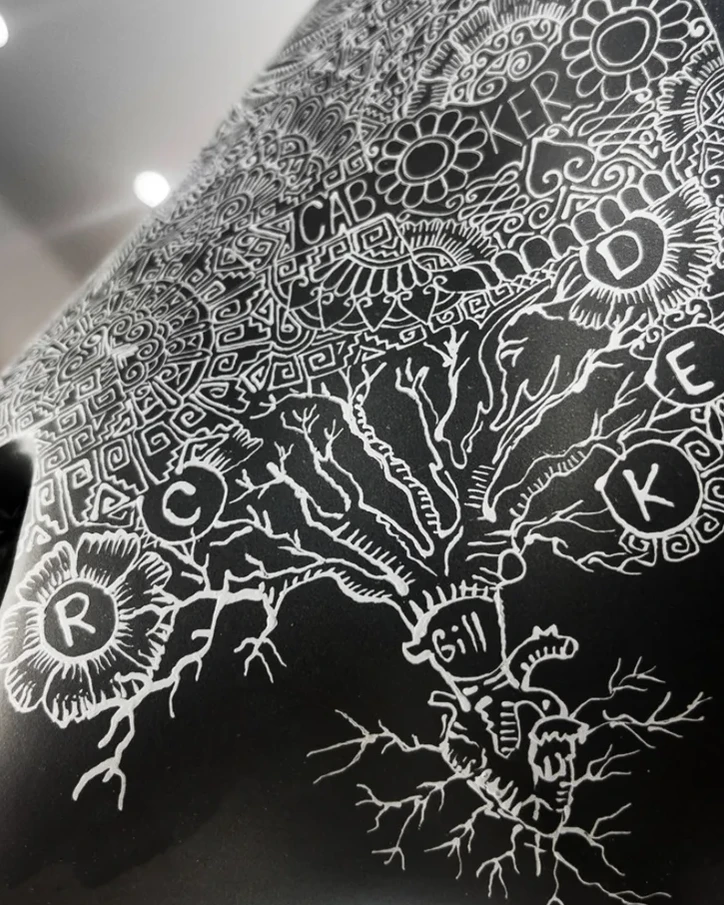 White tree branches and circled initials drawn on a black piece