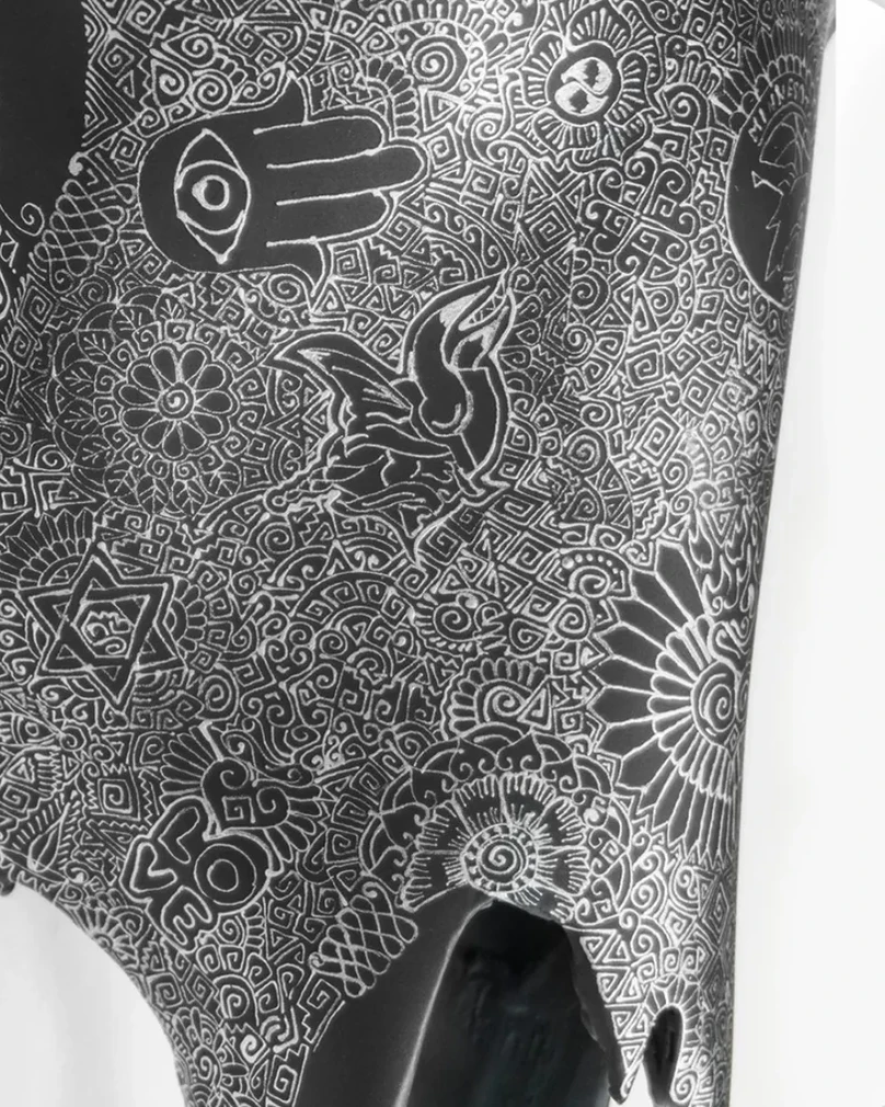 A hand motif and other illustrations in white linework on a black piece