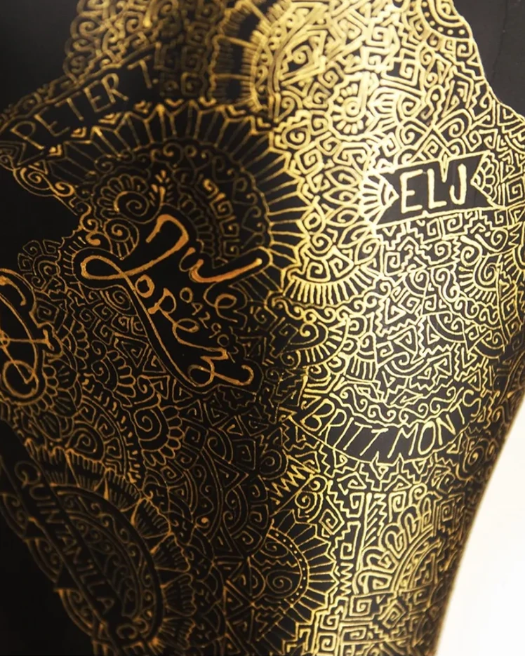 Golden initials and symbols drawn on a black commissioned artwork