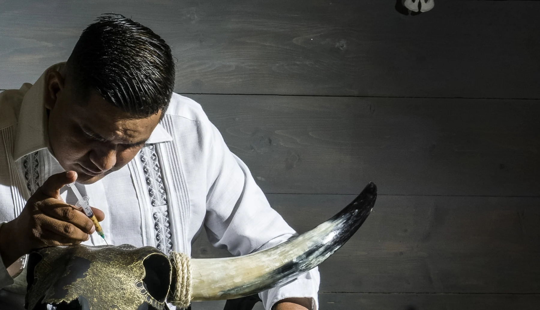 Ricardo Quero drawing fine details on a black and gold artwork