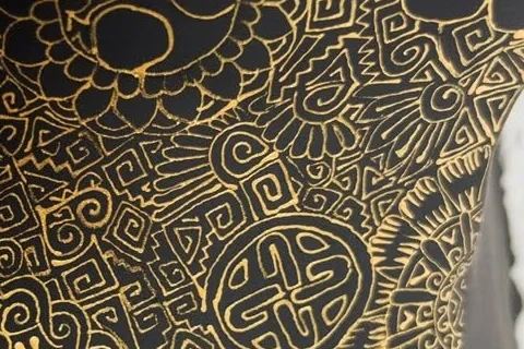 Angular spirals, stepped lines and floral symbols painted in gold on a black Cabokero artwork