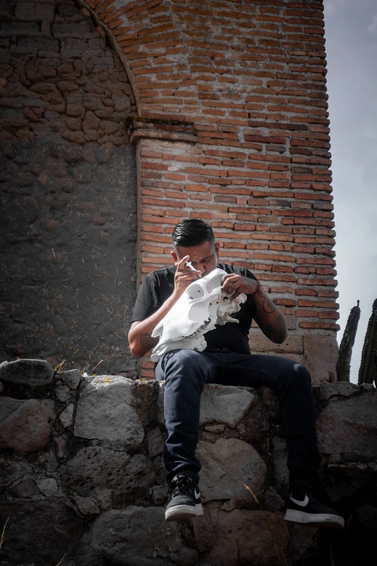 Ricardo seated among the stone walls of Mitla, holding one of his artworks